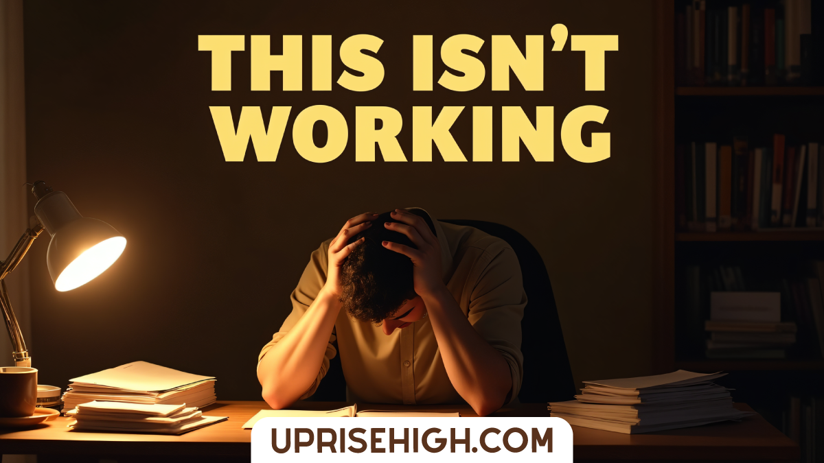A frustrated person holds their head in their hands at a desk surrounded by books and papers, with "THIS ISN'T WORKING" text overlay in a dimly lit study.